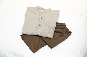 A neatly folded beige cardigan and brown pants on a white surface.