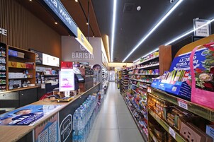 A grocery store aisle with a coffee shop on one side and a variety of products on the other.