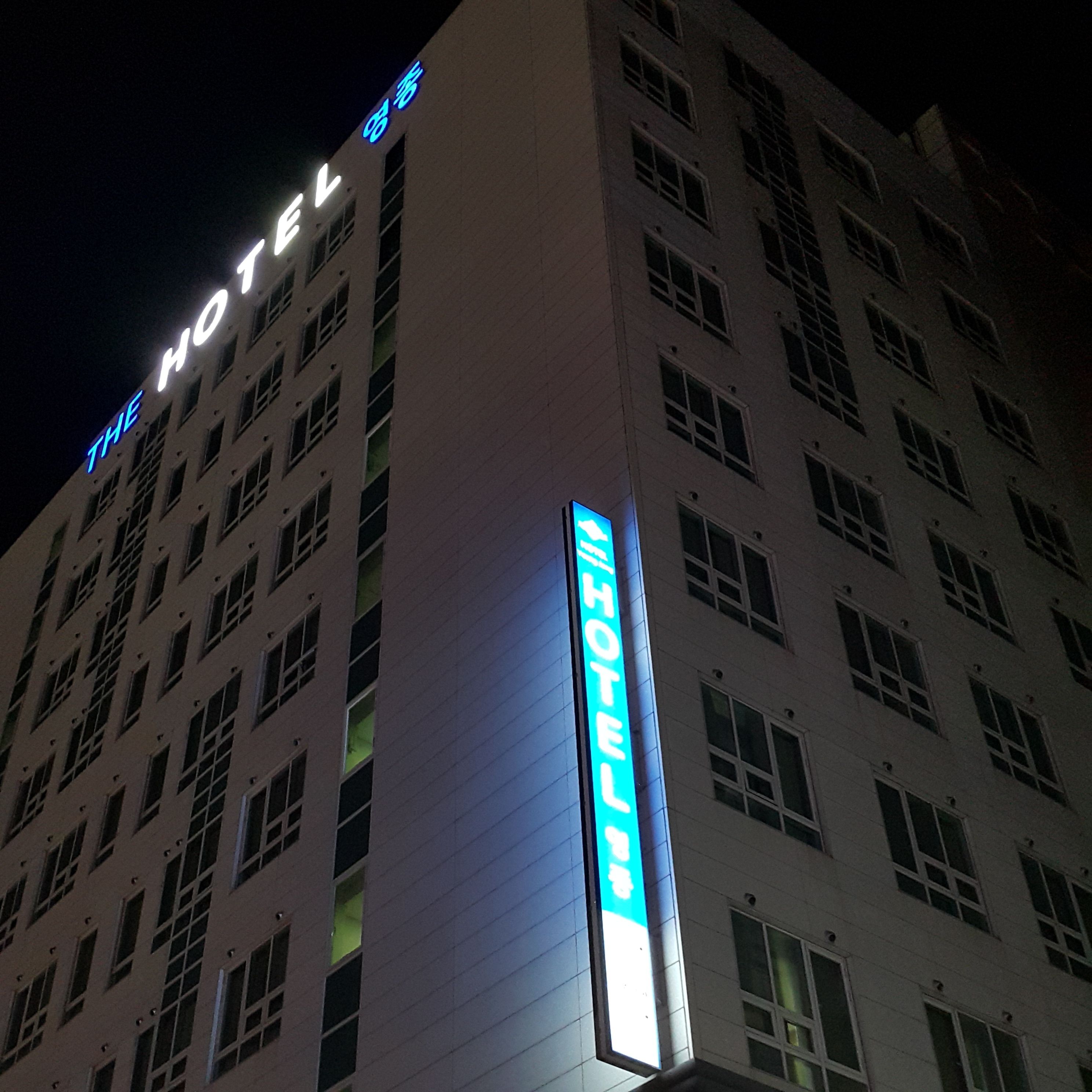A hotel building with illuminated signage reading "THE HOTEL" and "HOTEL".