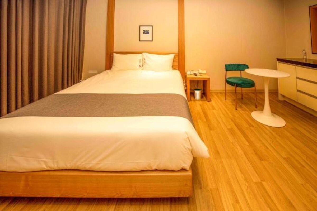 Habitación de hotel con una cama grande, un escritorio pequeño con teléfono, una silla y una mesita.