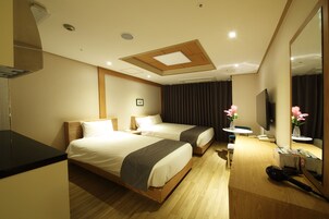 A hotel room with two beds, a desk, a mirror, and a TV.