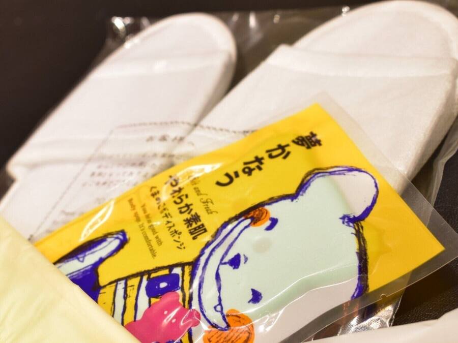 A package of white slippers with a yellow label and a cartoon character.