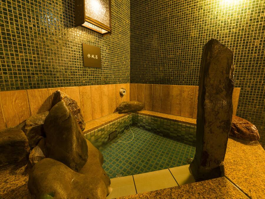 Un área pequeña con jacuzzi, detalles de madera y un cartel con el número de la habitación.
