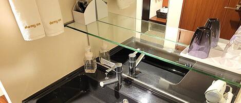 A bathroom with a glass shower enclosure, a black sink, and a mirror reflecting the room.
