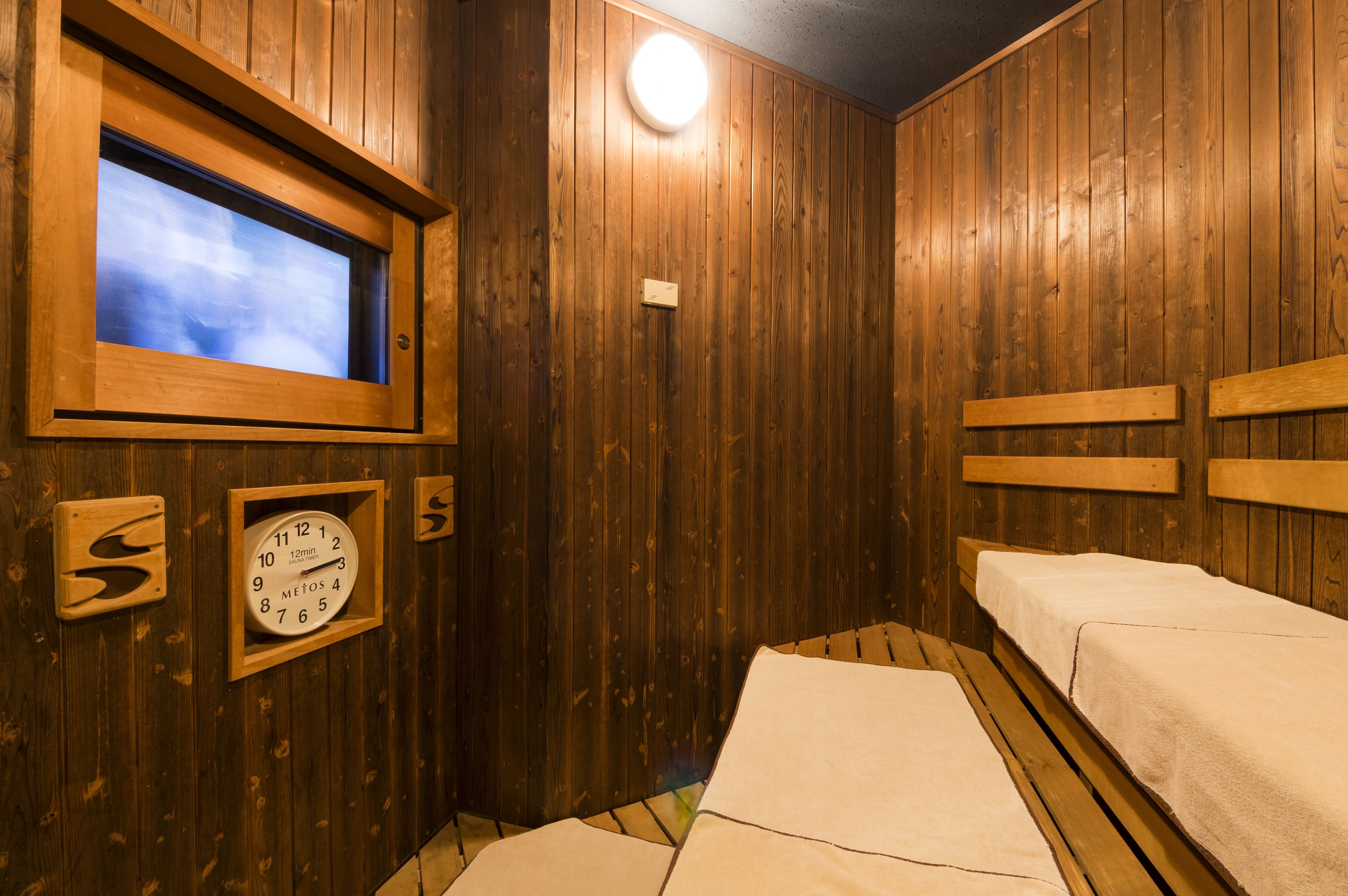 Een houten kamer met een groot raam, een klok en twee bedden.