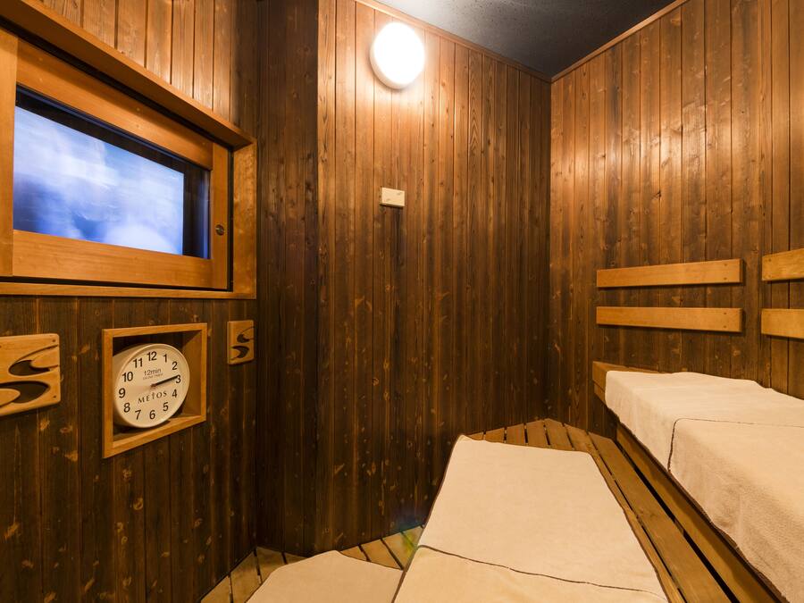 A wooden room with a large window, a clock, and two beds.