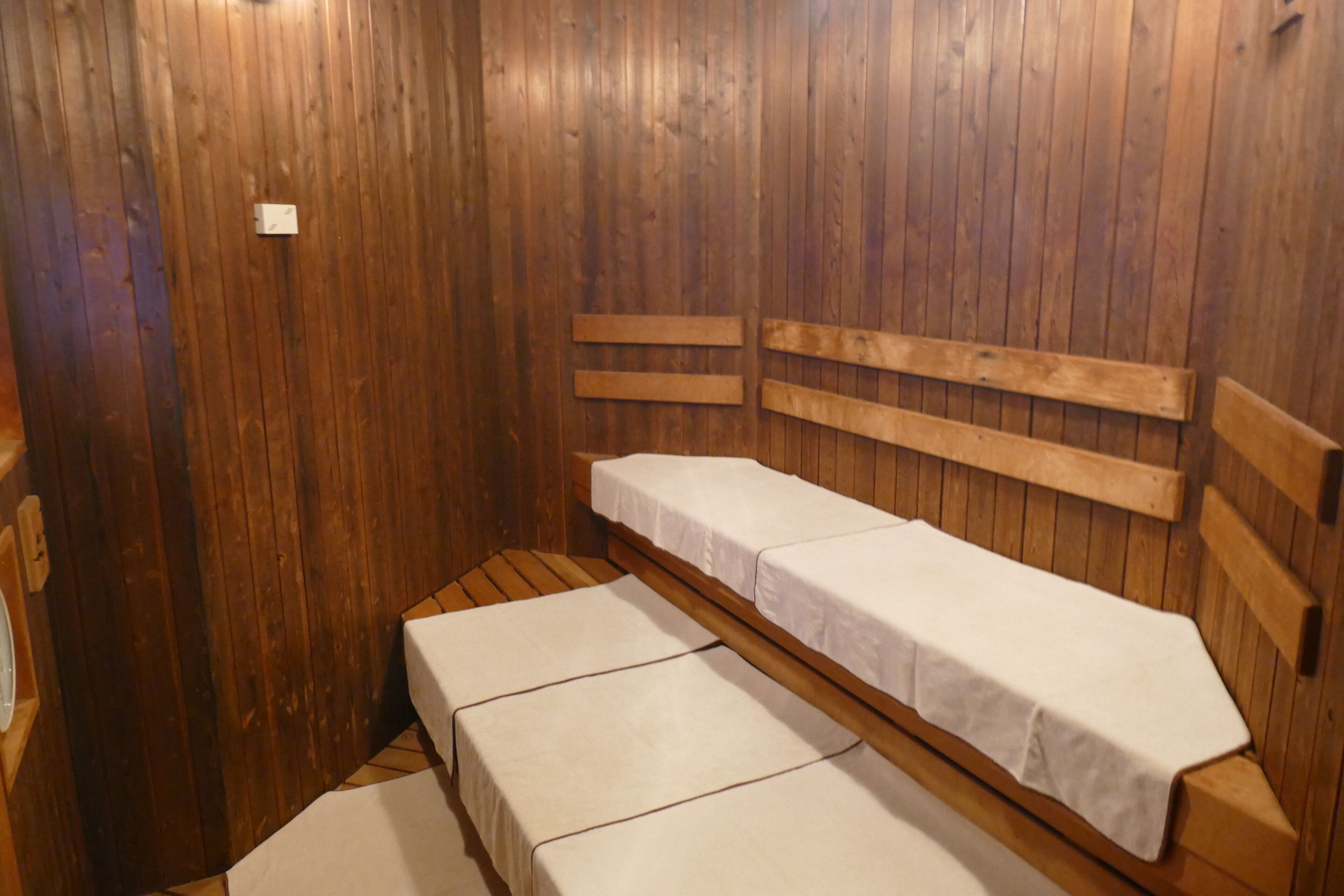 Eine Holzsauna mit Bänken, die mit weißen Laken bezogen sind.