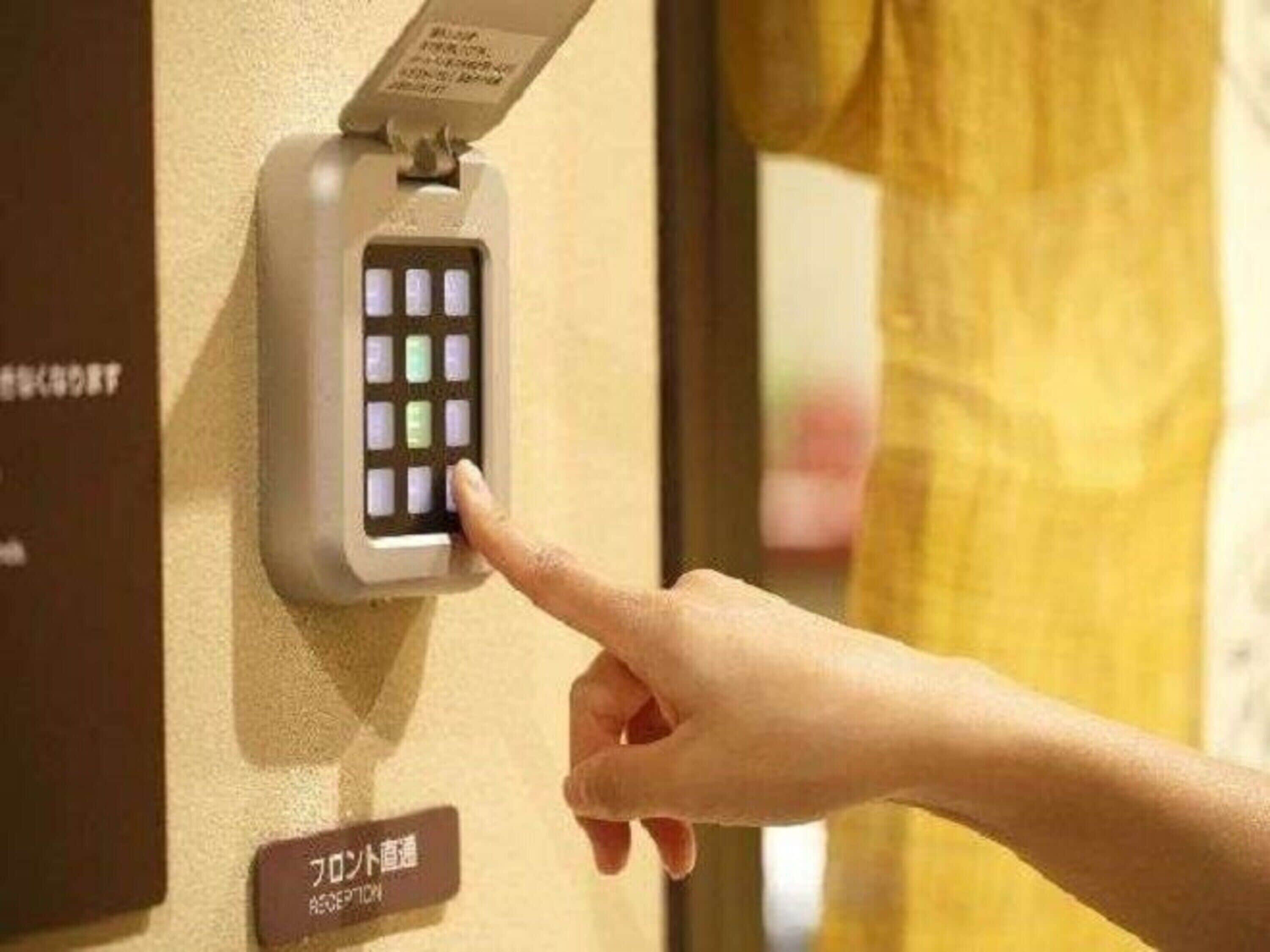 A hand pressing a button on a wall-mounted device with multiple illuminated buttons.