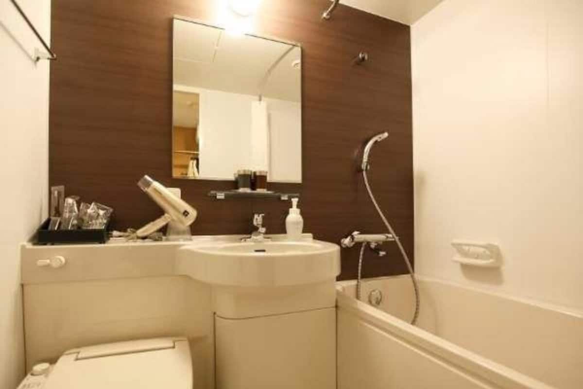 A bathroom with a toilet, sink, mirror, and shower.