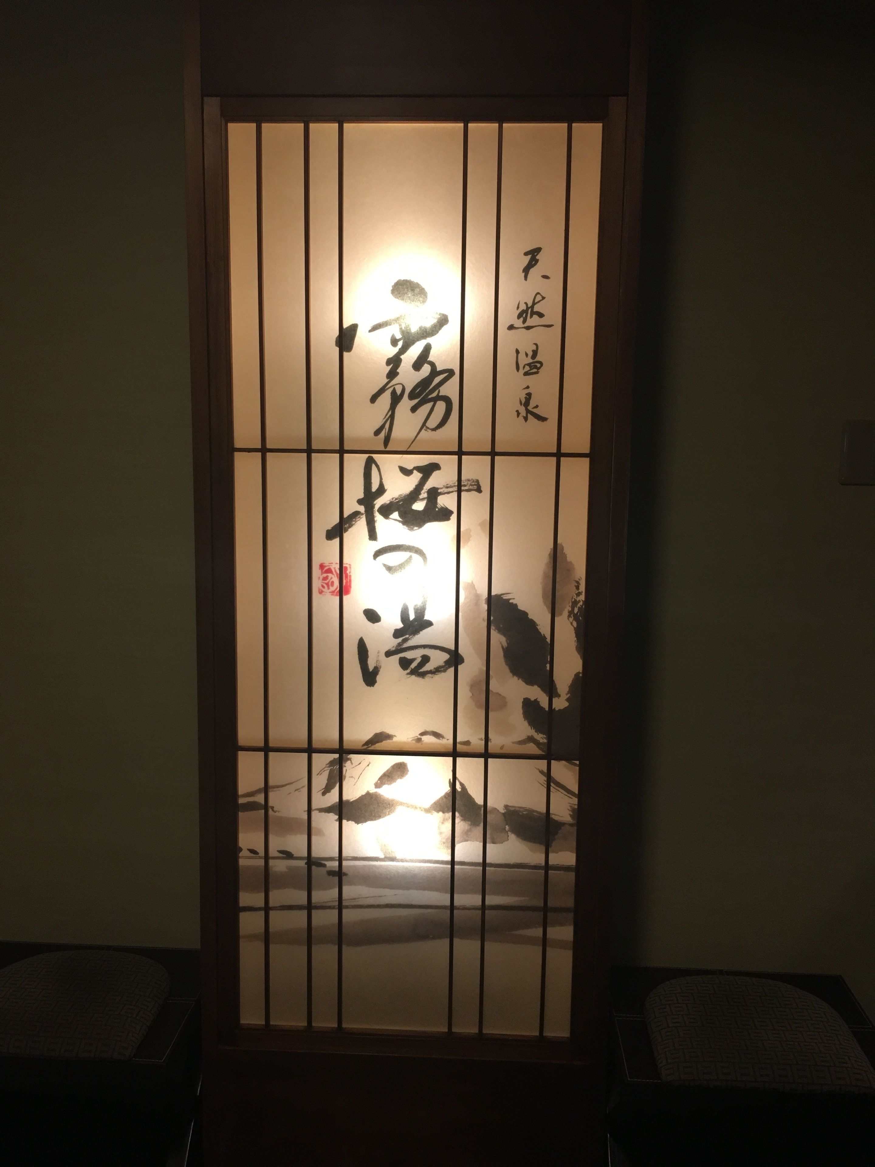Une porte coulissante japonaise traditionnelle ornée de calligraphie et d’un petit sceau rouge.