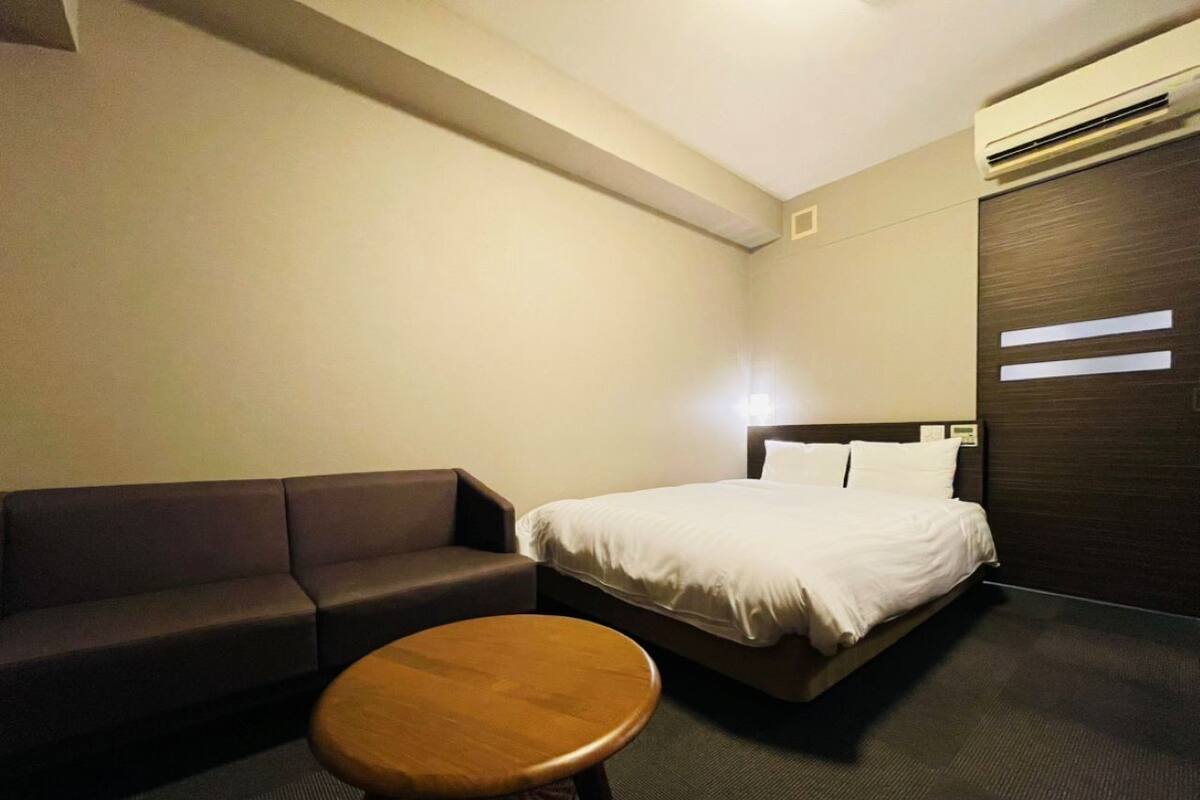A hotel room with a bed, a sofa, and a small round table.