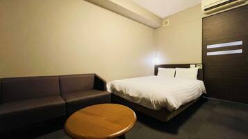A hotel room with a bed, a sofa, and a small round table.