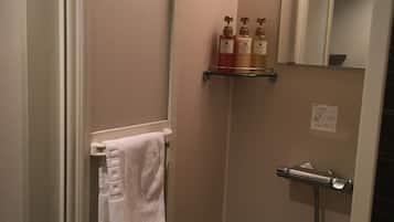A small bathroom with a glass shower enclosure, a towel rack with a white towel, and a shelf with toiletries.
