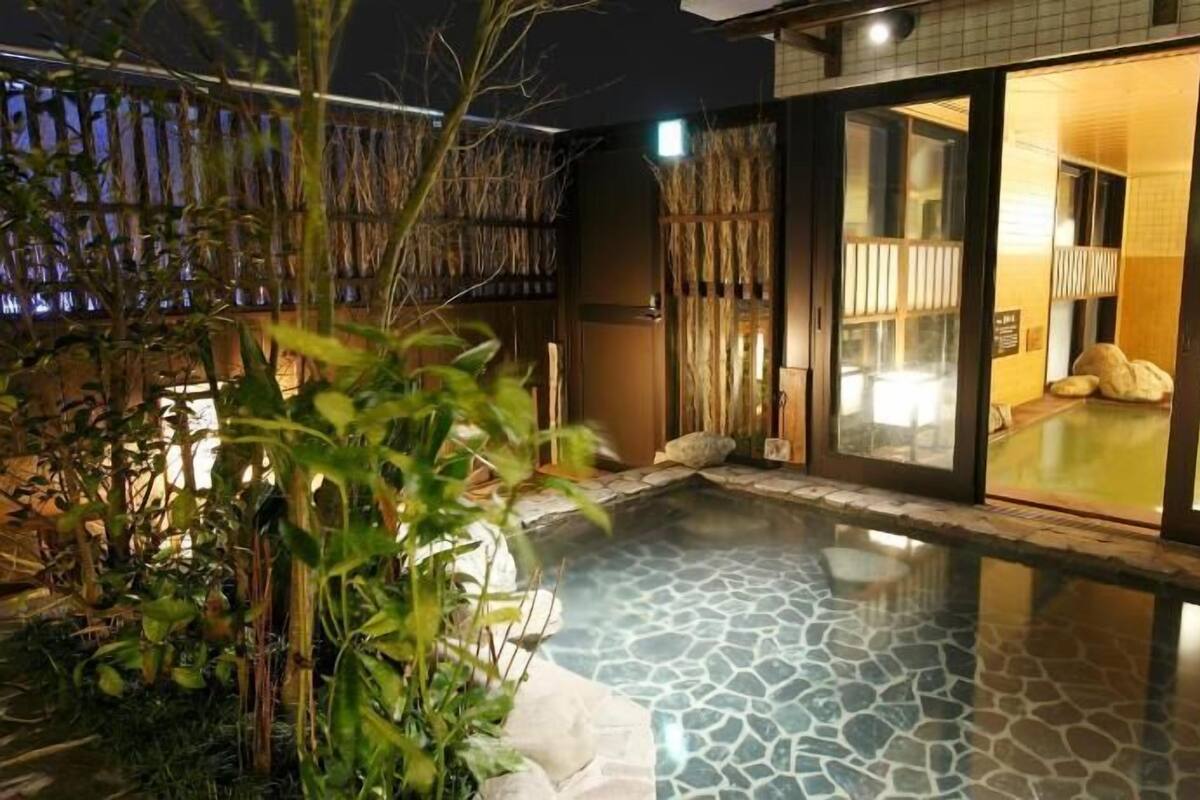 A private hot tub area with a stone floor, surrounded by a bamboo fence and plants.