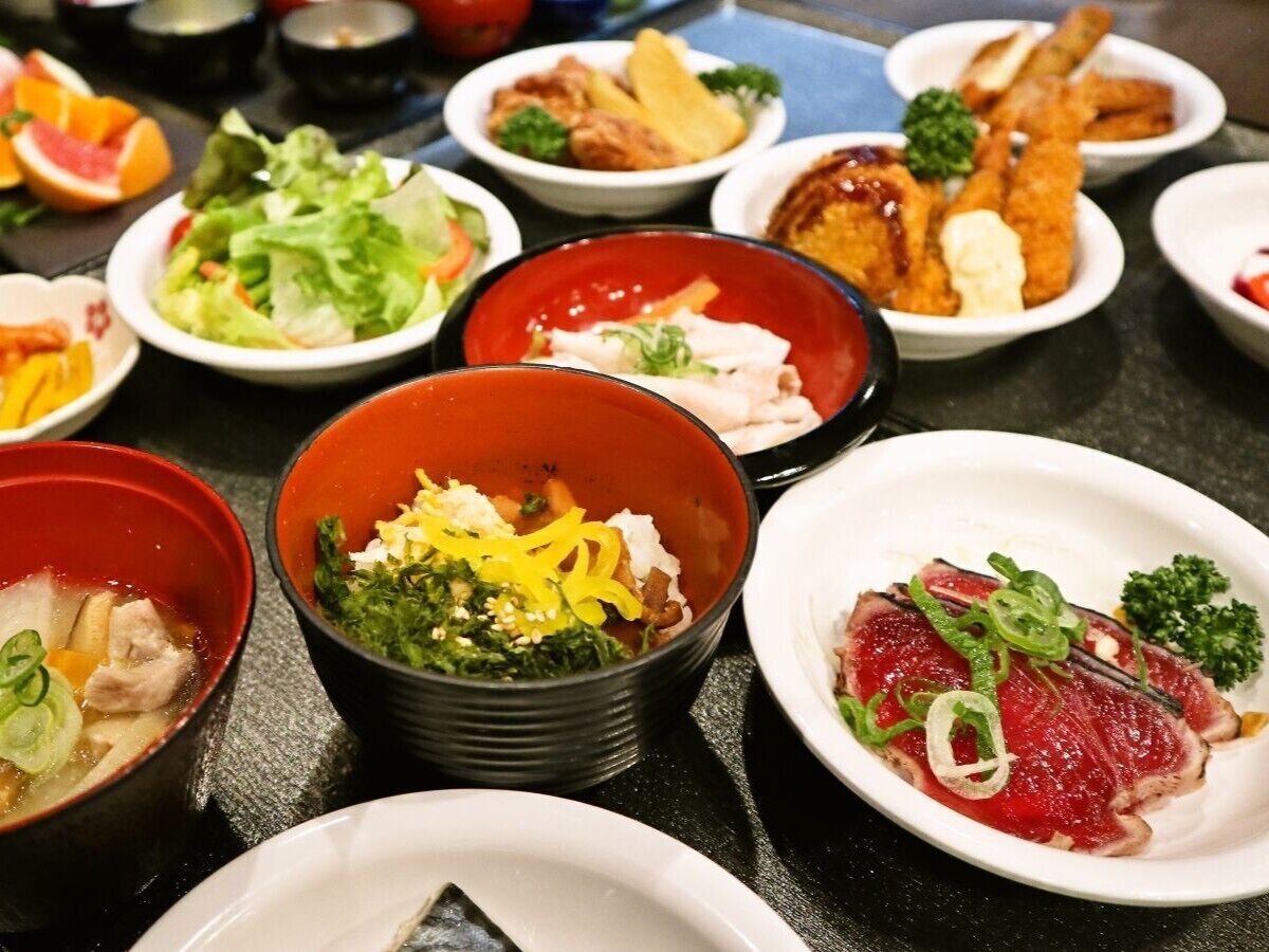A variety of dishes on a table, including a bowl of soup, a plate of sashimi, and several small bowls with different foods.