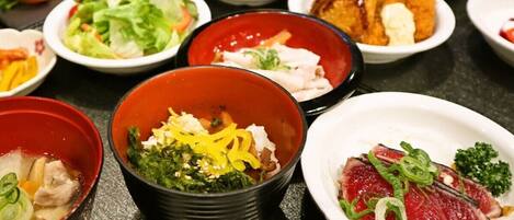 A variety of dishes on a table, including a bowl of soup, a plate of sashimi, and several small bowls with different foods.