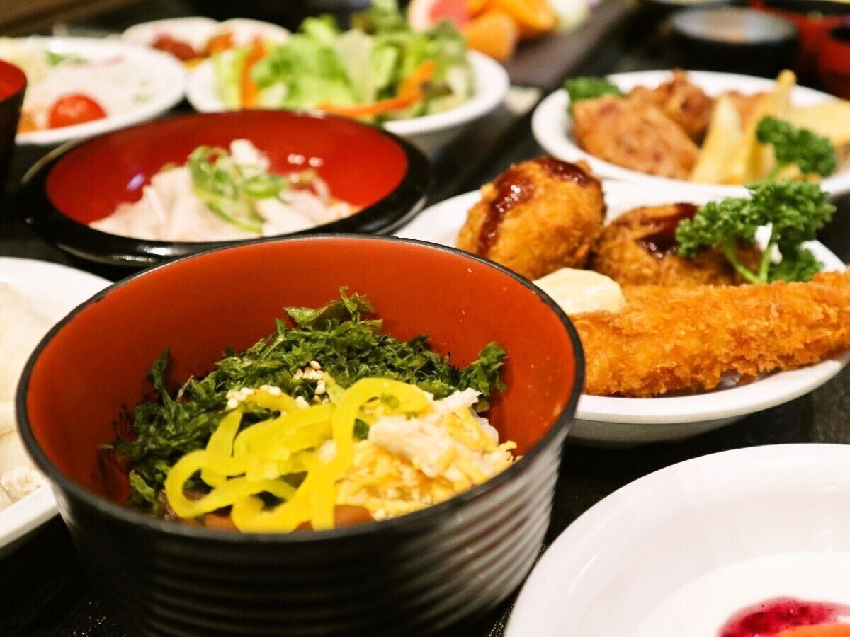 A variety of dishes in bowls, including a salad with greens and yellow strips, and a breaded item.