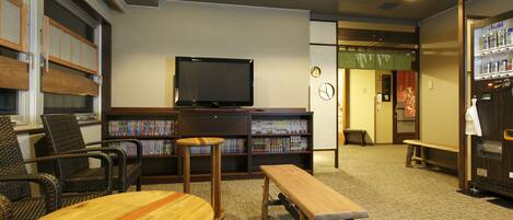 A library with bookshelves, a television, and seating areas.