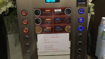 Une machine à café Nescafé offrant de nombreuses options de boissons, notamment du café chaud et du café glacé, ainsi qu’un avertissement concernant les éclaboussures de café dans la glace.