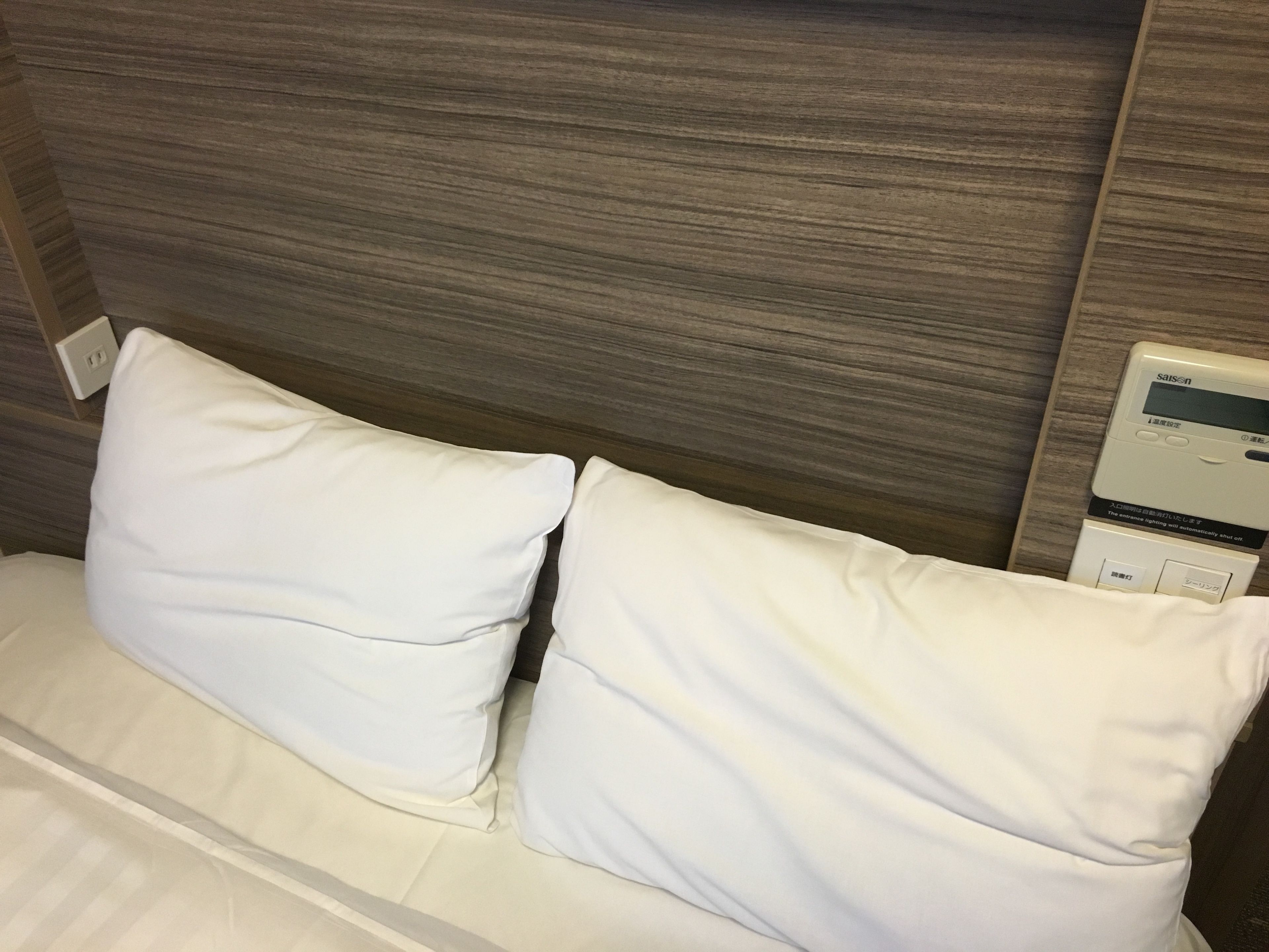 A bed with white bedding and a headboard with a built-in control panel.