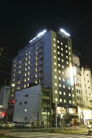 Um hotel com vários andares, janelas iluminadas e uma placa indicando que se trata de um hotel para negócios.