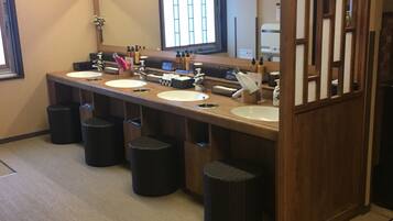 A hotel bathroom with three sinks, a large mirror, and a wooden partition.