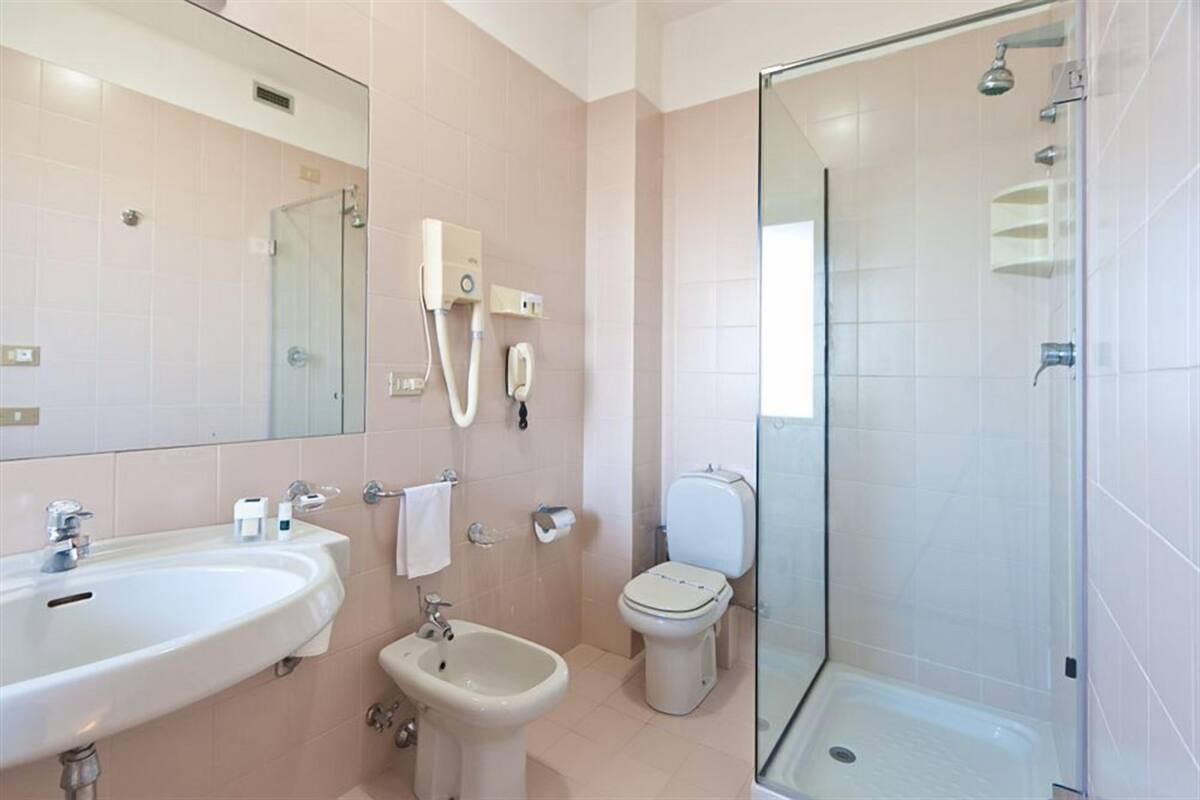 A modern bathroom with a sink, bidet, toilet, and glass-enclosed shower.