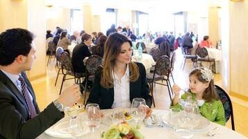 Una sala da pranzo formale con diversi tavoli, sedie e ospiti.
