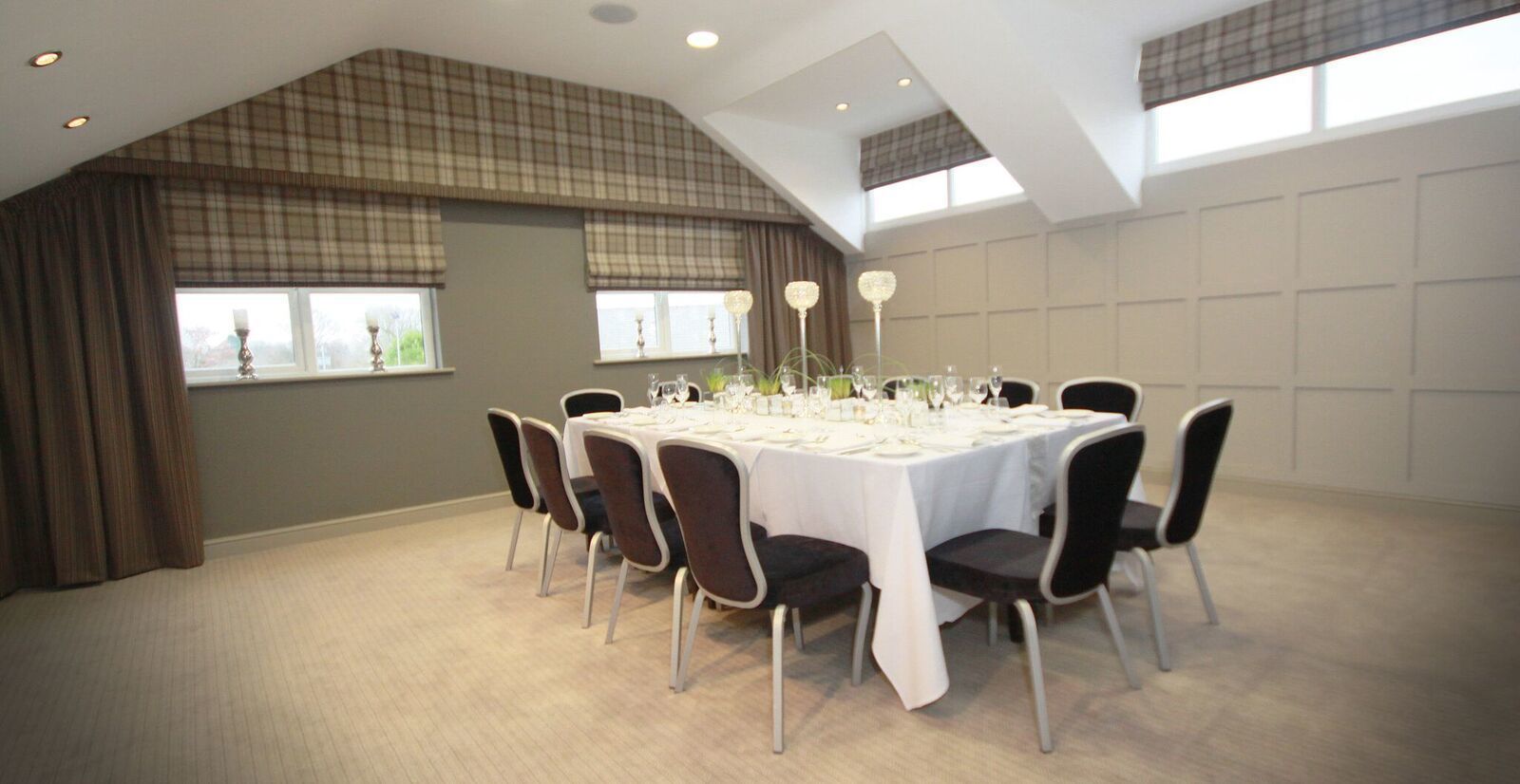 Un espace repas doté d’un haut plafond, de grandes fenêtres et d’une table dressée pour six personnes.