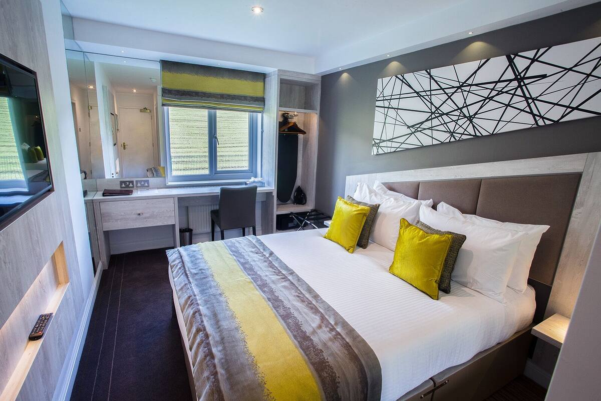 Quarto de hotel moderno com uma cama grande, uma escrivaninha e uma cadeira.