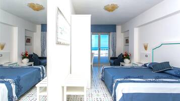 Habitación de hotel con dos camas, un balcón y vista al mar.