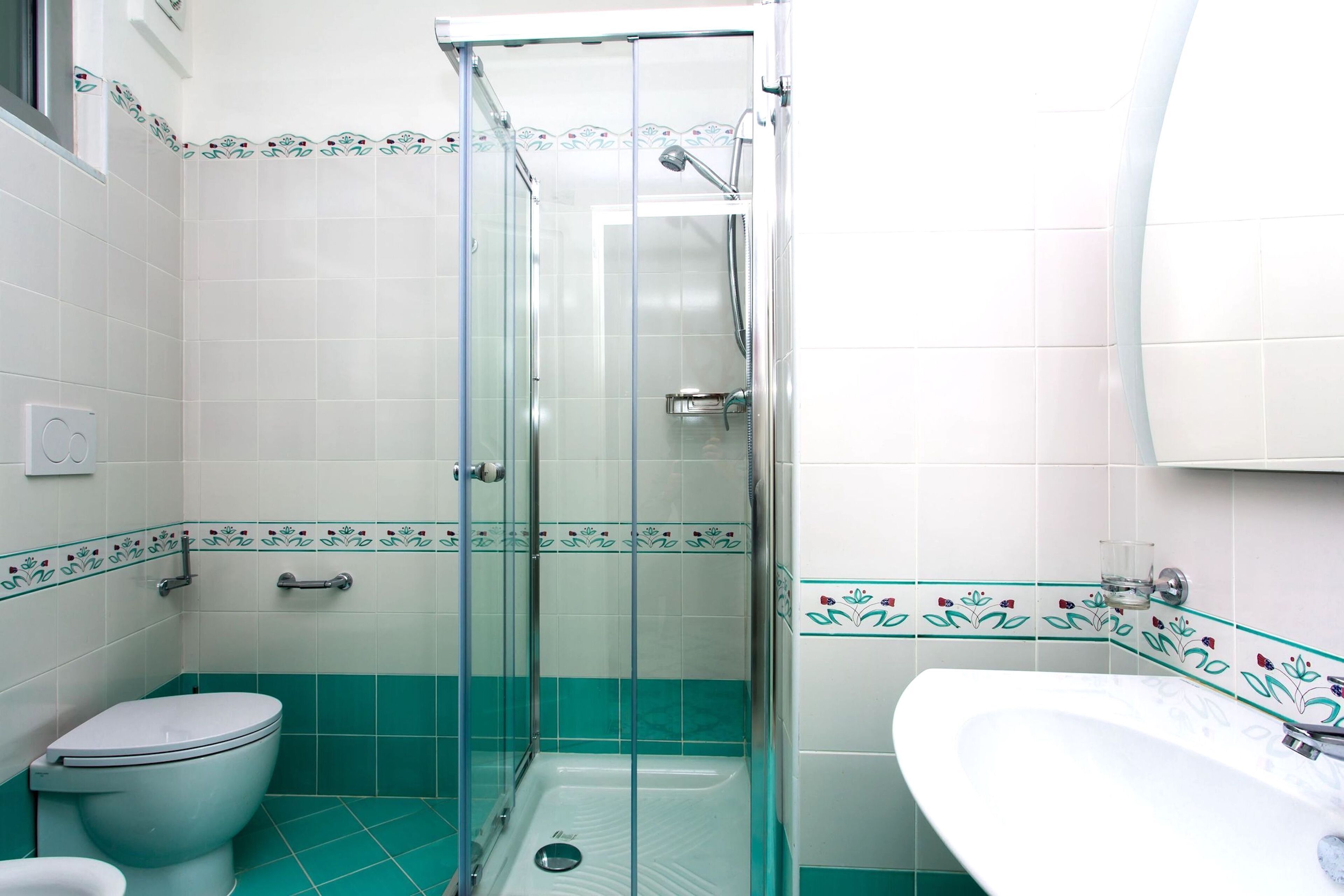 Un baño con ducha de vidrio, inodoro y lavamanos.