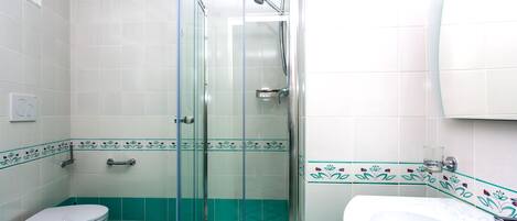 A bathroom with a glass-enclosed shower, a toilet, and a sink.