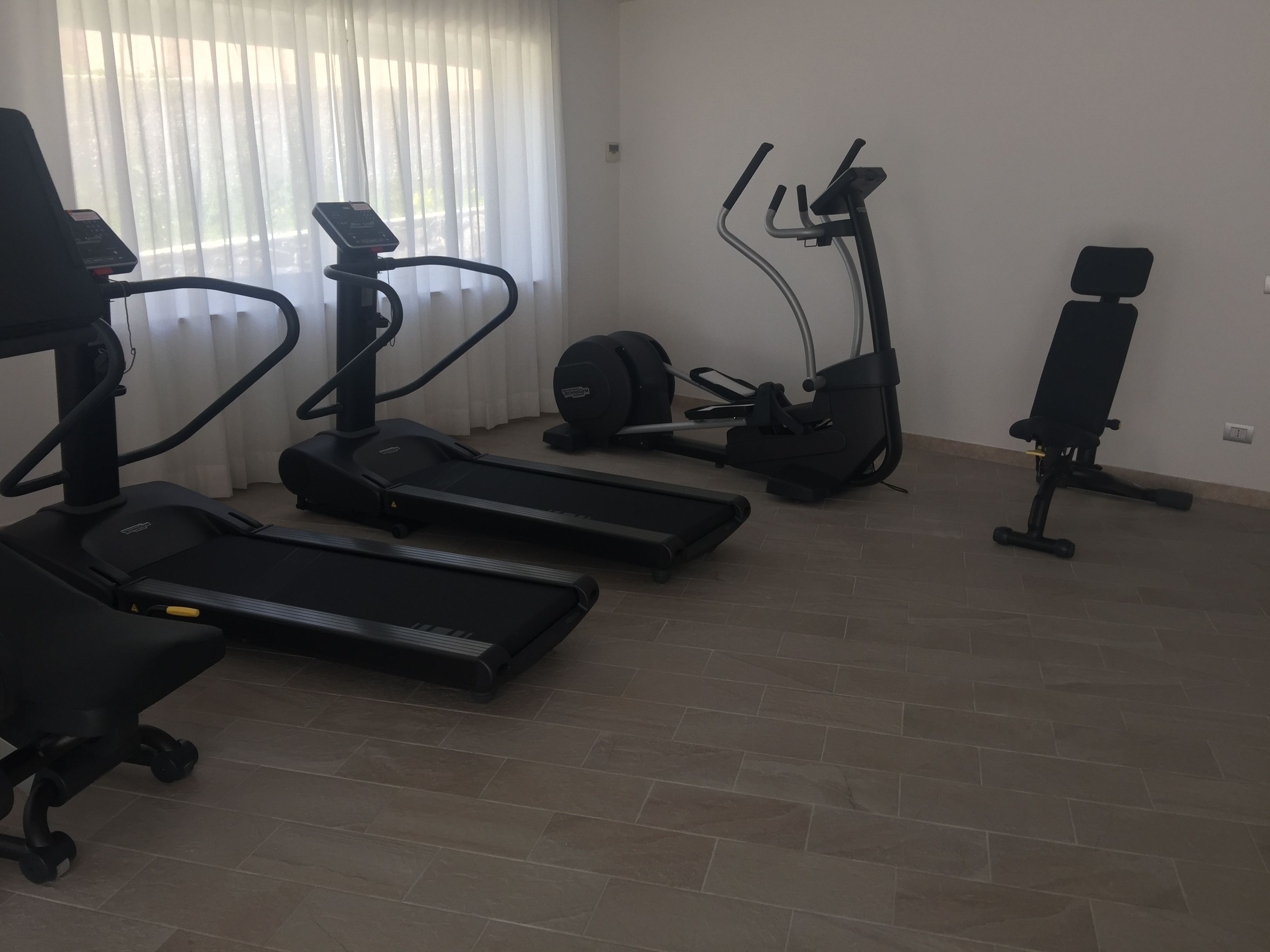 Et hjemmegymnasium med løbebånd, crosstrainer og motionscykel.