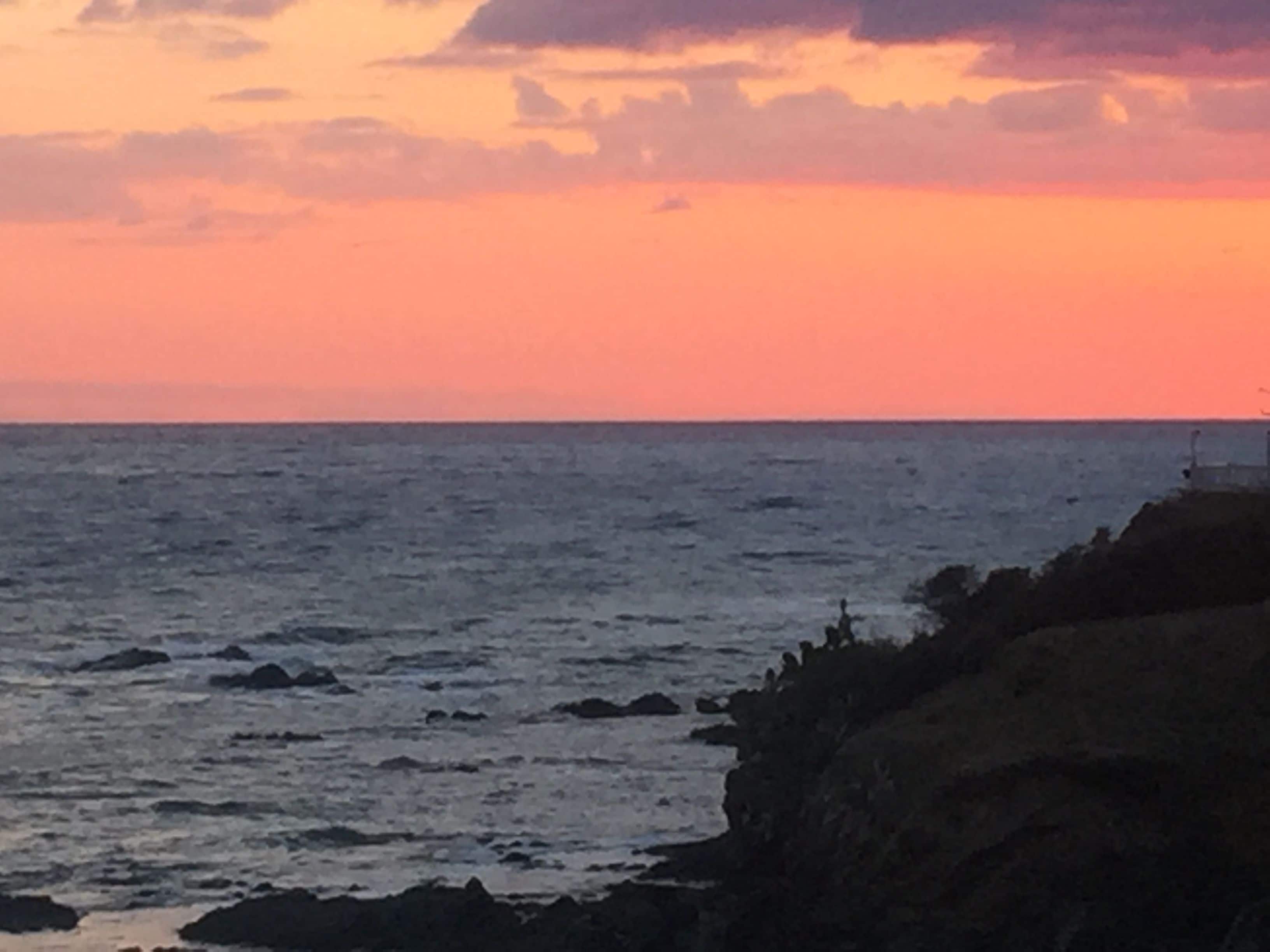 A coastal scene with a rocky shoreline and a clear view of the sea.