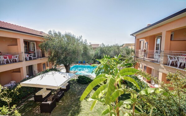 A courtyard with a swimming pool, outdoor seating, and a covered area.