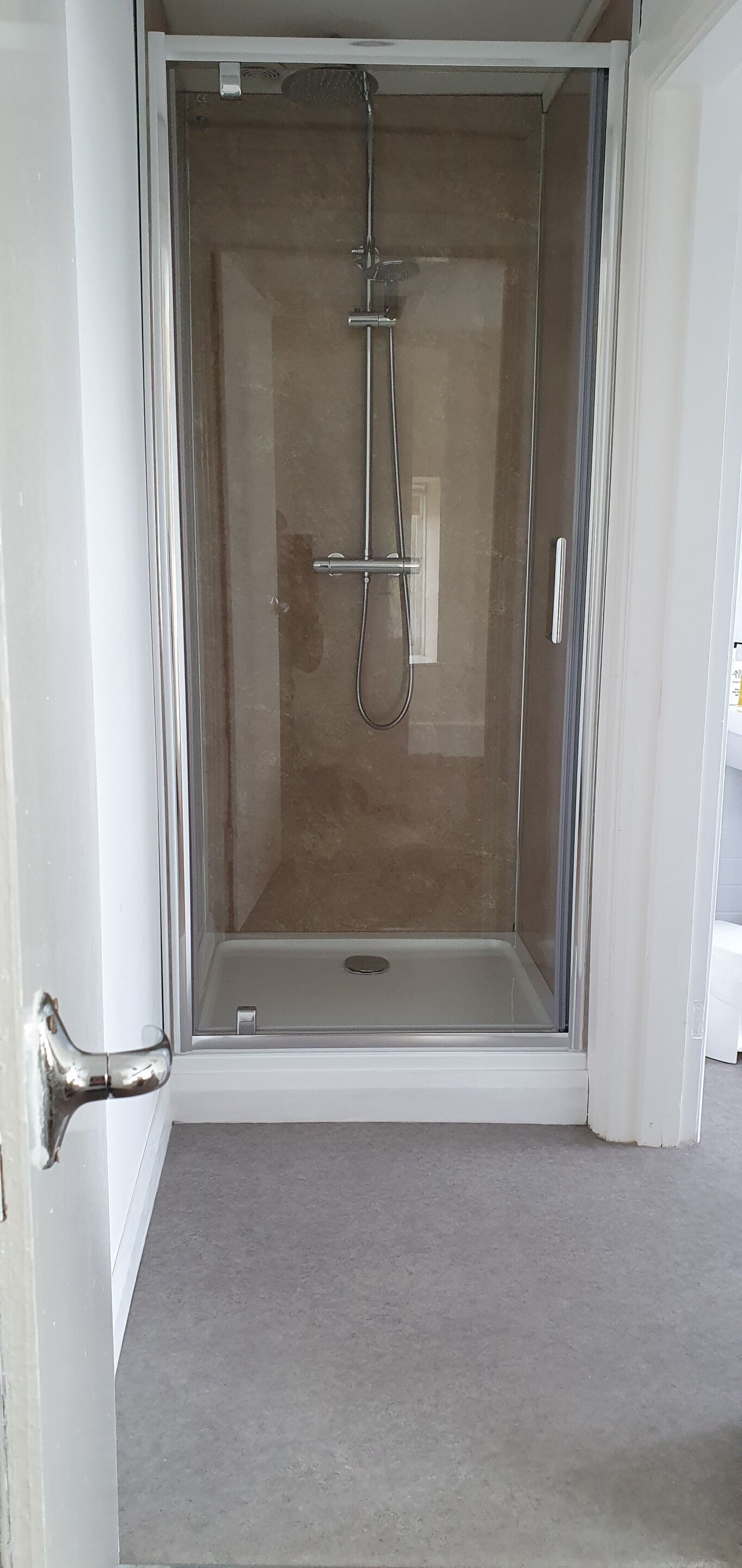 A glass-enclosed shower area with a showerhead and control panel.
