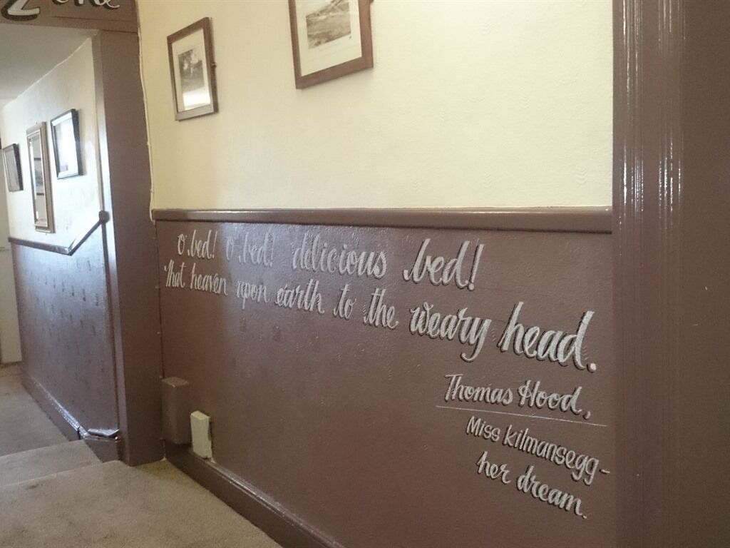 A hallway with a wall featuring a quote by Thomas Hood.