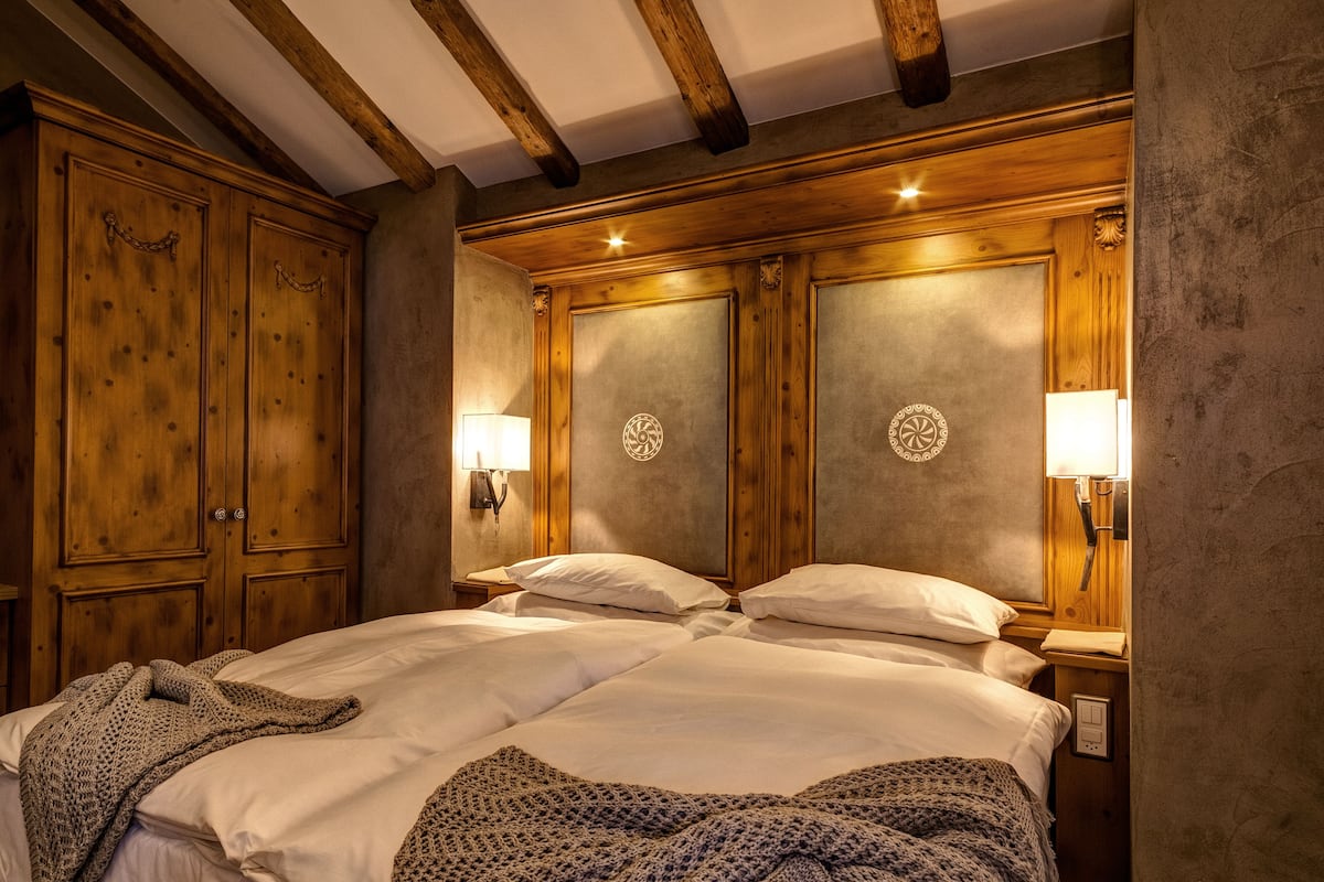 A bedroom with a large bed, wooden wardrobe, and two bedside lamps.