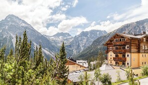 A mountain lodge with a wooden facade, multiple balconies, and a view of snow-capped mountains. - BelArosa Hotel (Arosa)