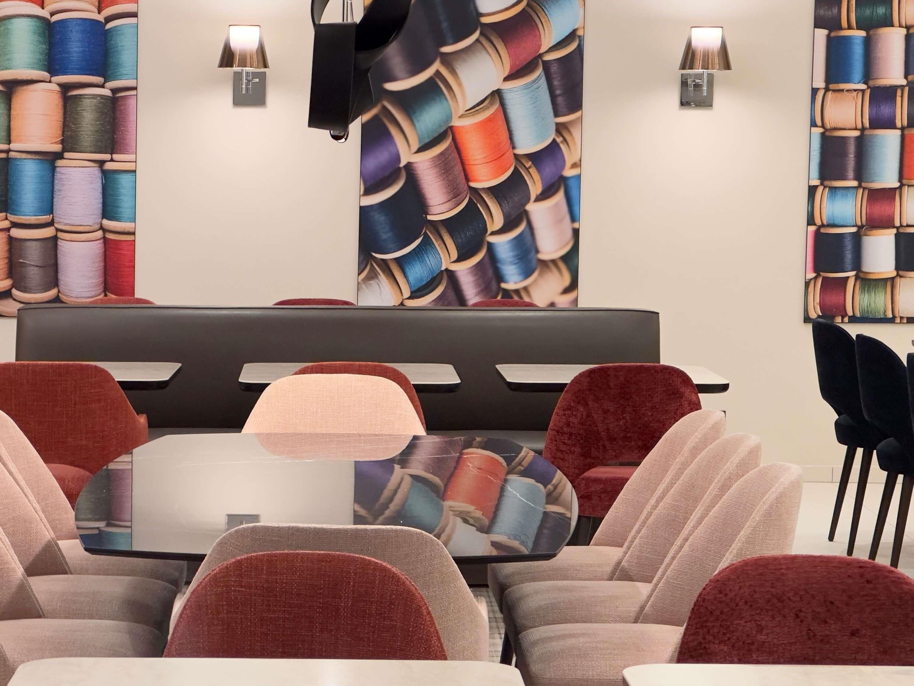 Un espace de détente moderne avec une table centrale, des fauteuils confortables et des murs décorés de grandes peintures représentant des bobines.