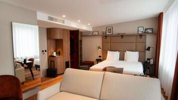 Habitación de hotel con sofá, cama, escritorio, armario y mesita de noche.