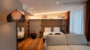 Habitación de hotel con cama, sofá, escritorio y espejo.
