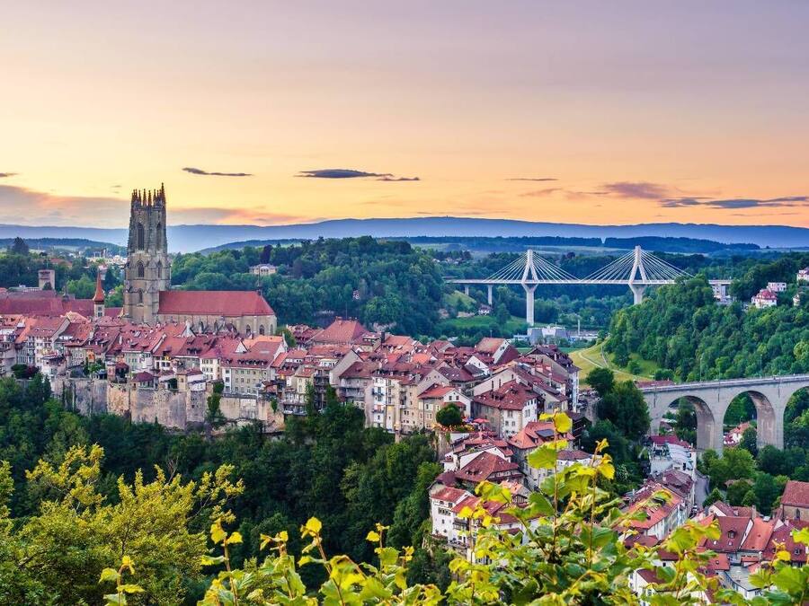 A historic town with a prominent church, a bridge, and a river.