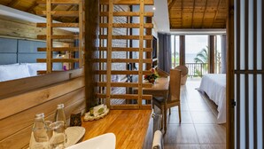 A wooden-framed room with a bed, a dining table with chairs, and a view of the ocean. - Hotel Isla del Encanto (Cartagena)