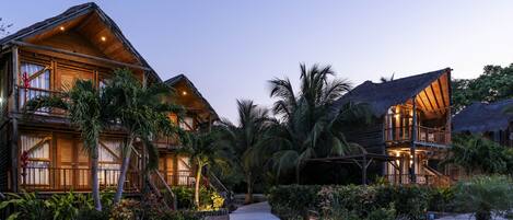 A resort with wooden buildings, a paved walkway, and tropical landscaping.