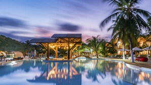 A serene pool area with a wooden deck, lounge chairs, and a palm tree. - Hotel Isla del Encanto (Cartagena)