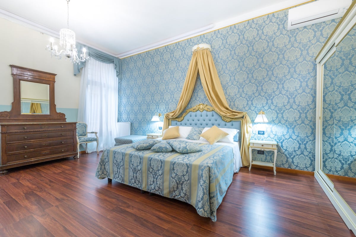 A bedroom with a large bed, a dresser, a chair, and a mirror.