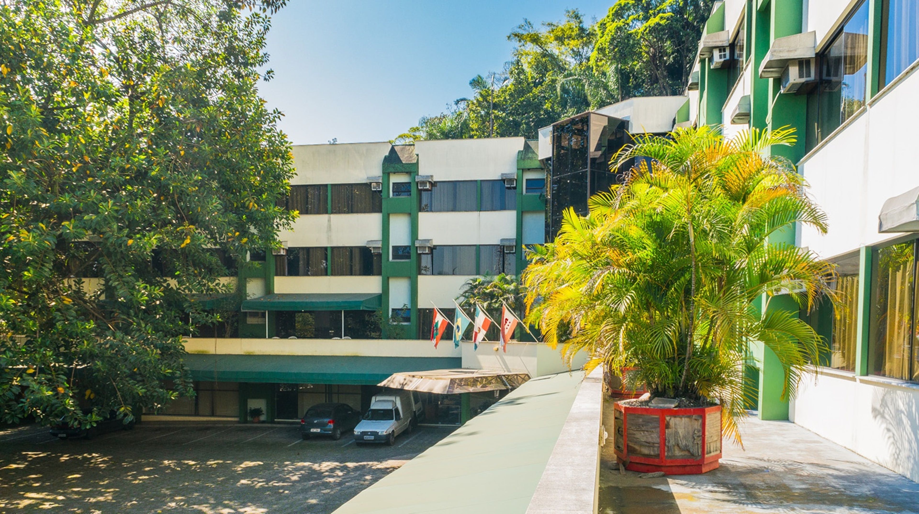 Un patio con un edificio verde, un área de estacionamiento y una planta en maceta.