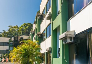 A multi-story building with green and white exterior walls, air conditioning units, and a clear sky.